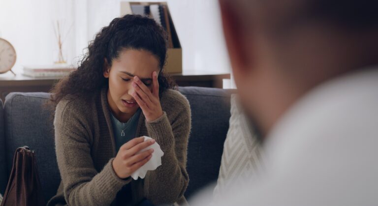 Woman, sad or crying on sofa by psychologist employee or healthcare worker in mental health, anxiet